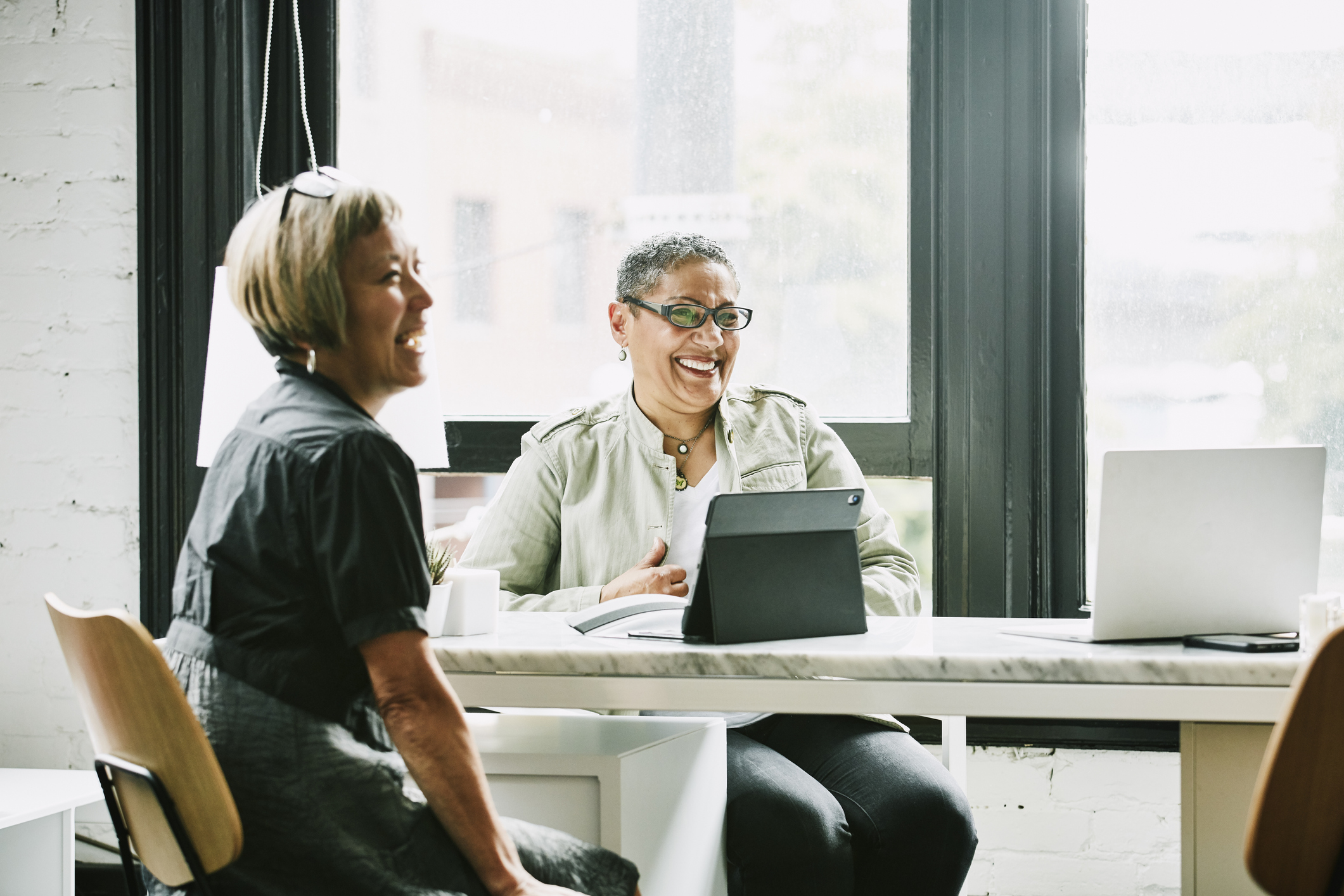 laughing mature women discovering connection between zero-interest loans, patient satisfaction, and provider returns in corporate hospital