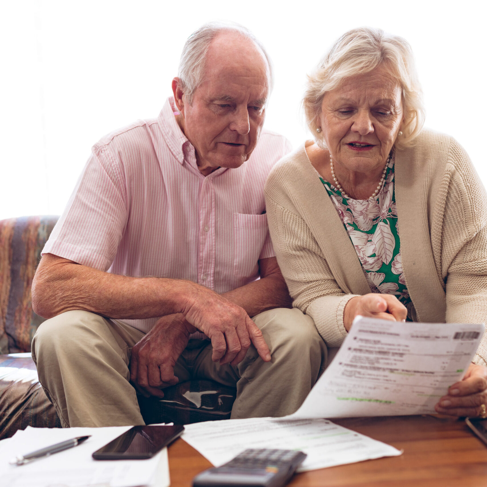 Couple discussing over medical bill while sitting on sofa Couple discussing over medical bill while sitting on sofa