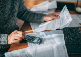 close up of patient differentiating between zero-interest patient financing vs. medical credit cards, reviewing many medical bills with calculator
