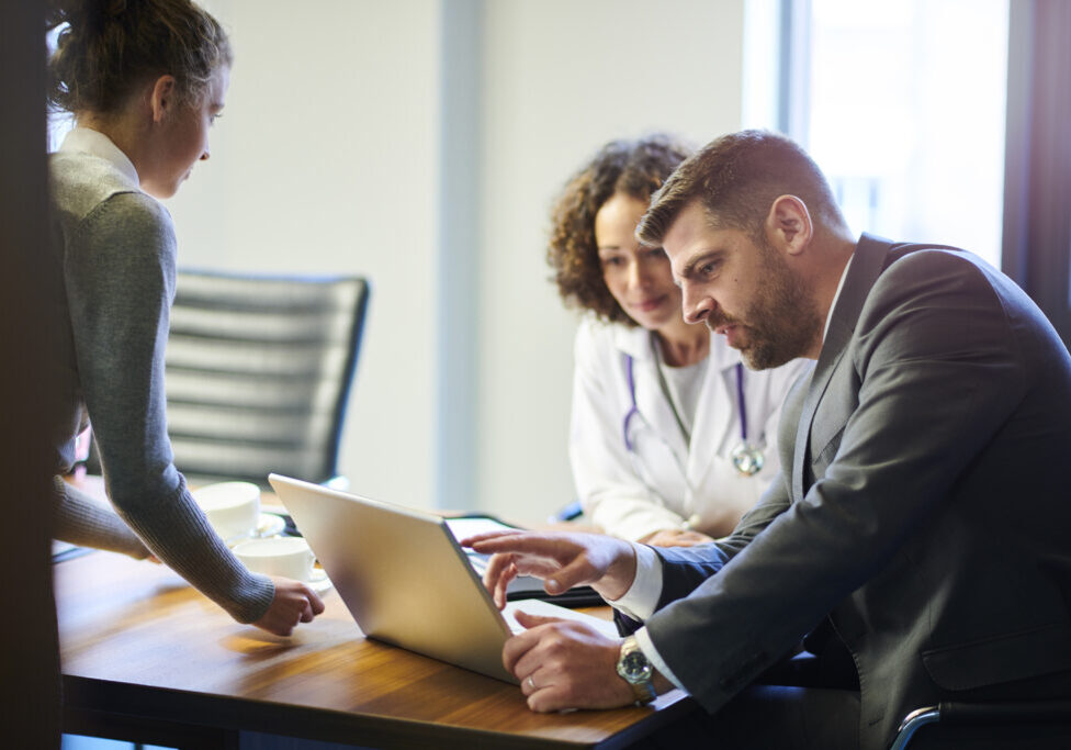 a businessman chats with a female doctor as they leave a boardroom meeting in a hospital