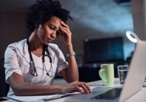 stressed provider about health system bad debt at computer and desk with head in hand