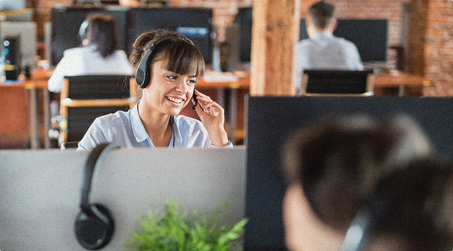 woman in healthcare financing solutions support team wearing headset and happily takikng calls at the office