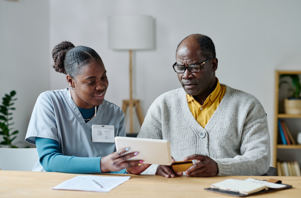 nurse showing senior patient healthcare billing technologies while he pays his medical bill