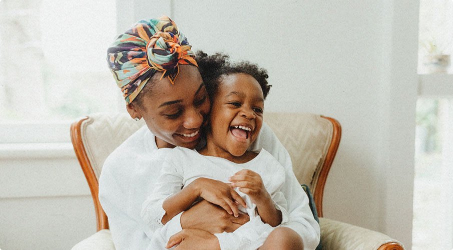 happy mother with young child in chair smiling because of healthcare financing company helping with medical expenses